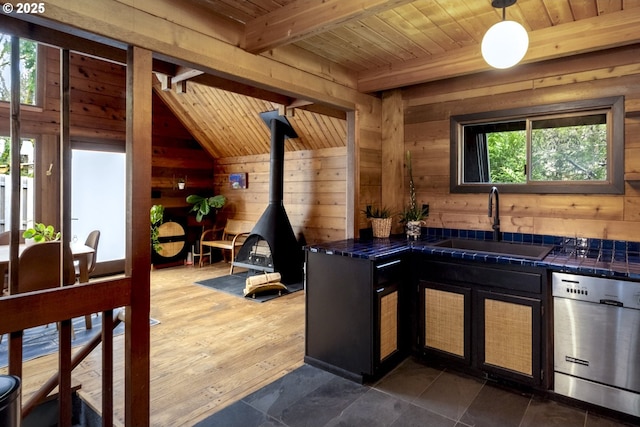 kitchen with a sink, stainless steel dishwasher, wood ceiling, and wood walls