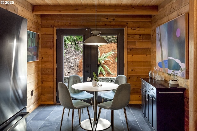 dining area featuring beam ceiling, wooden walls, and wood ceiling