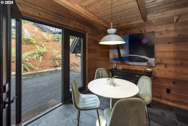 unfurnished dining area featuring dark tile patterned floors, wooden walls, and wood ceiling