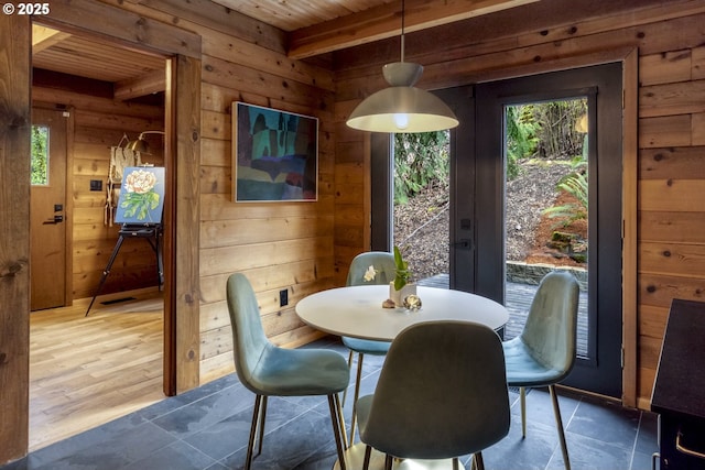 dining room with visible vents, wood walls, beam ceiling, wooden ceiling, and french doors