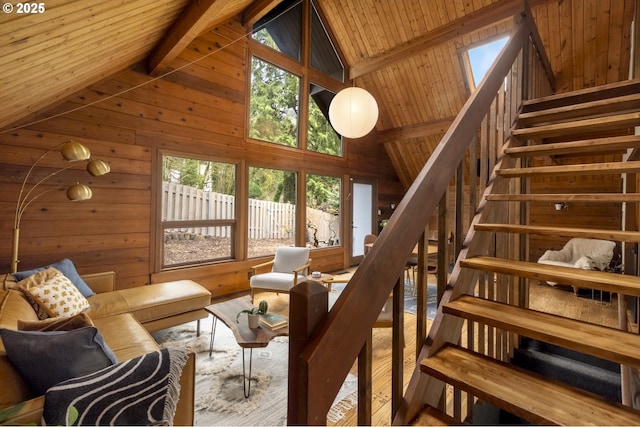 living area with stairway, wood finished floors, beam ceiling, wood ceiling, and wood walls