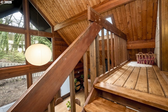 stairway featuring beam ceiling, wooden walls, wood ceiling, and high vaulted ceiling