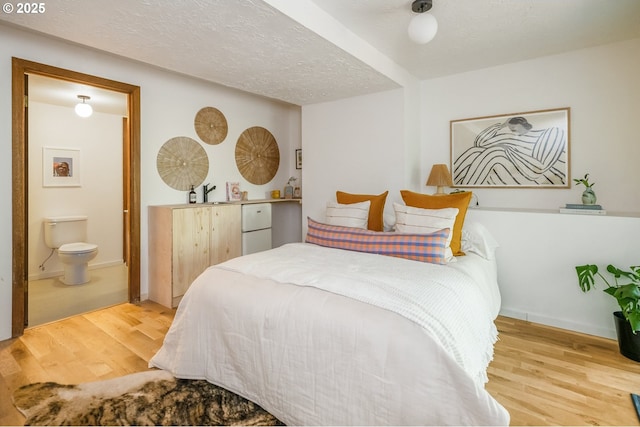 bedroom featuring a textured ceiling, ensuite bath, and wood finished floors