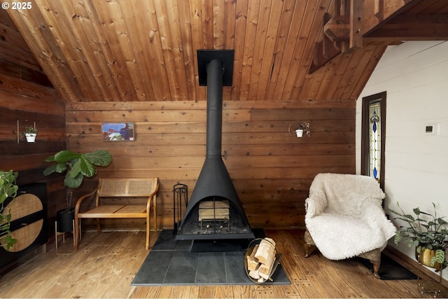 living area featuring wooden walls, a wood stove, lofted ceiling, and hardwood / wood-style flooring