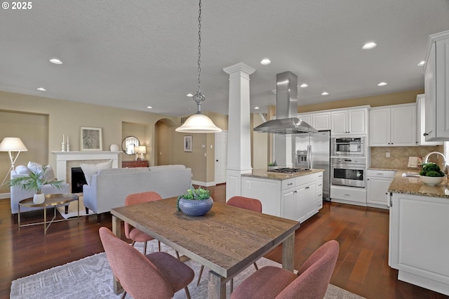 13129 NW Alvada St, Portland, OR 97229 - dining area featuring arched walkways, a fireplace, dark wood finished floors, and recessed lighting