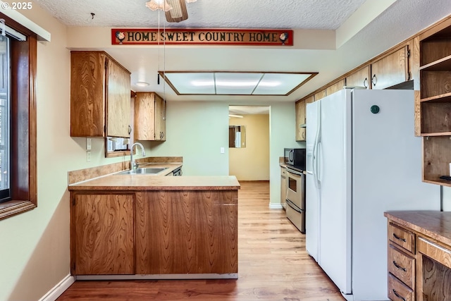 kitchen with a textured ceiling, white refrigerator with ice dispenser, light hardwood / wood-style floors, sink, and stainless steel electric range