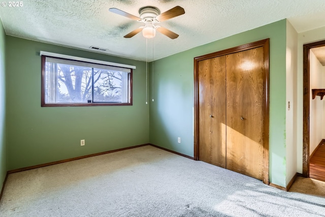 unfurnished bedroom featuring a closet, ceiling fan, carpet, and a textured ceiling