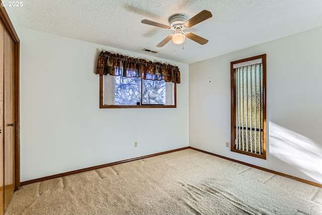 carpeted empty room featuring ceiling fan and a textured ceiling