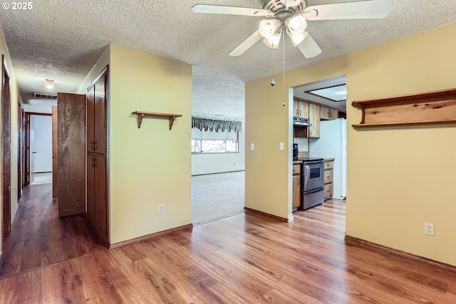 interior space with electric stove, wood-type flooring, white refrigerator, and a textured ceiling