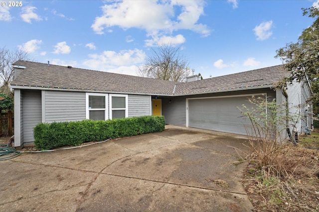 ranch-style home with a garage, concrete driveway, a chimney, and a shingled roof