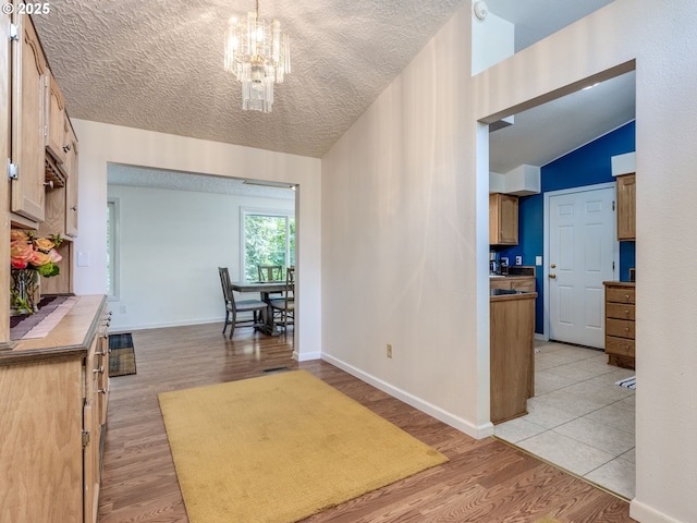 12309 SE Riveridge Dr, Vancouver, WA 98683 - hallway featuring light wood finished floors, a chandelier, lofted ceiling, baseboards, and a textured ceiling