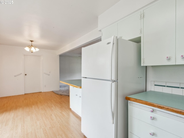 4118 SE 132nd Ave, Portland, OR 97236 - kitchen with freestanding refrigerator, light wood-style floors, white cabinetry, a chandelier, and hanging light fixtures