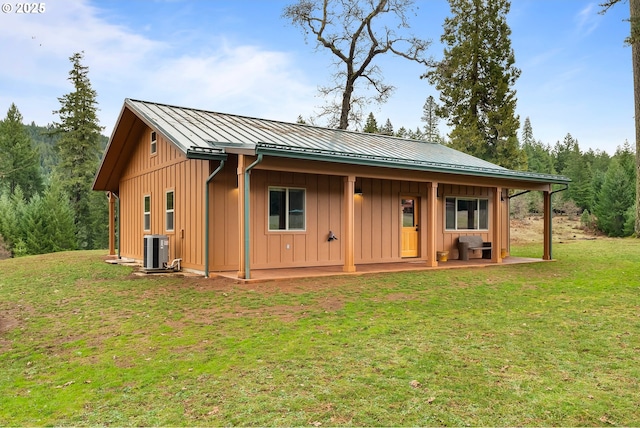 rear view of house featuring central AC and a lawn