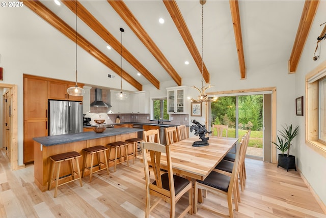 dining room with sink, an inviting chandelier, light wood-type flooring, high vaulted ceiling, and beam ceiling