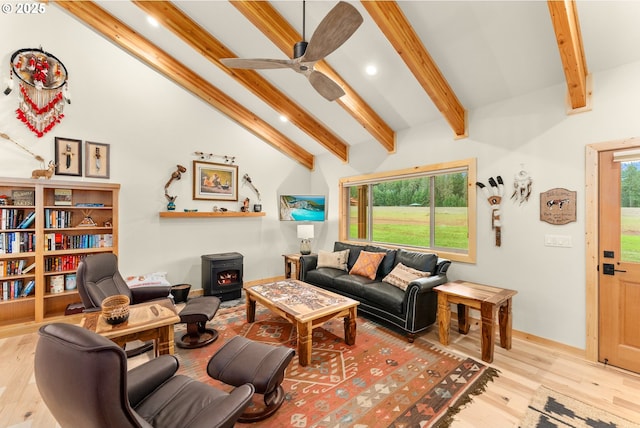 living room with ceiling fan, light hardwood / wood-style flooring, vaulted ceiling with beams, and a wood stove