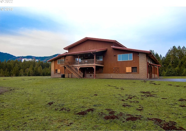 back of property featuring a yard and a deck with mountain view