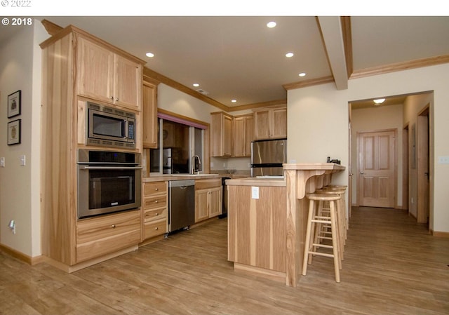 kitchen with a breakfast bar, light brown cabinetry, beam ceiling, and appliances with stainless steel finishes