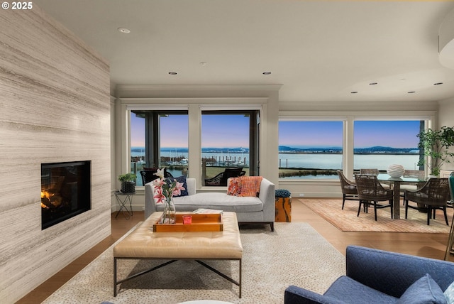 living area with recessed lighting, a water view, a fireplace, and wood finished floors