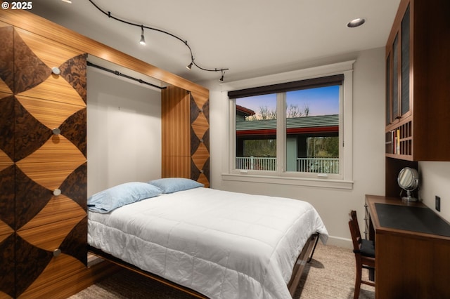 bedroom featuring rail lighting, carpet flooring, and baseboards