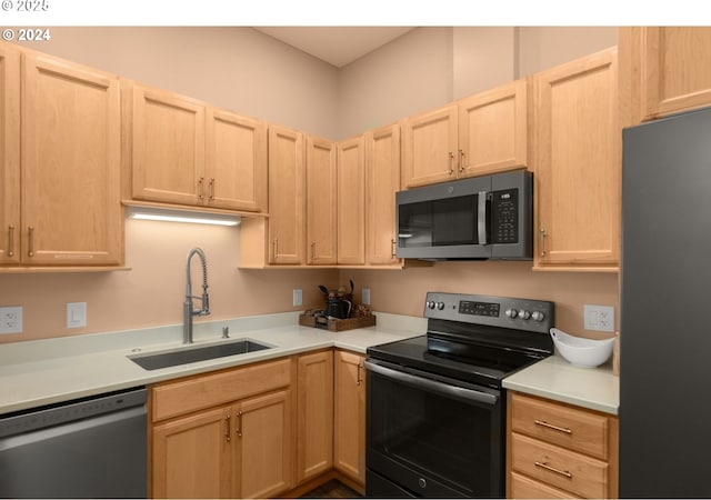 kitchen featuring light brown cabinets, range with electric cooktop, a sink, freestanding refrigerator, and dishwasher