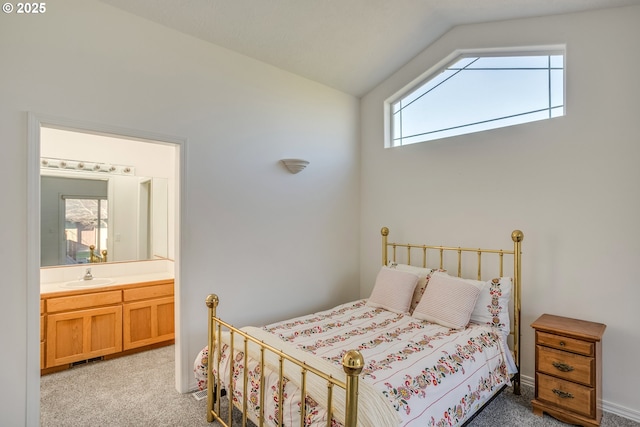 bedroom with ensuite bath, vaulted ceiling, light carpet, and a sink