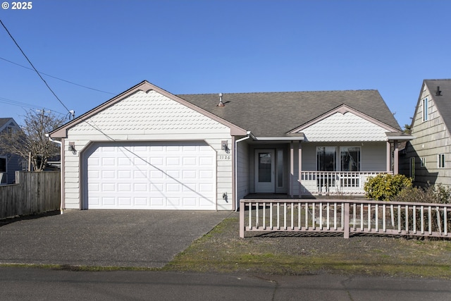 view of front of home with covered porch, driveway, a garage, and fence