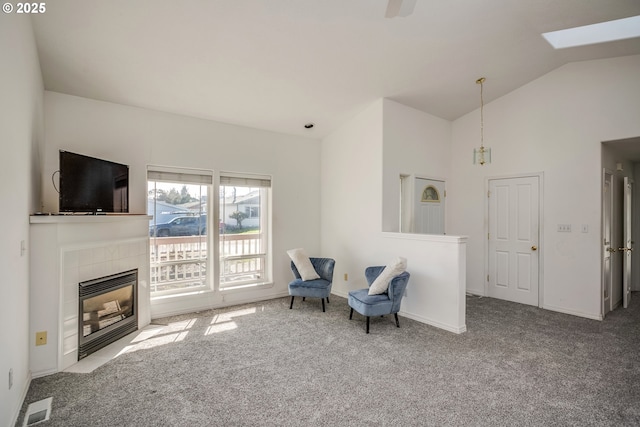 sitting room with vaulted ceiling with skylight, visible vents, carpet flooring, and a fireplace