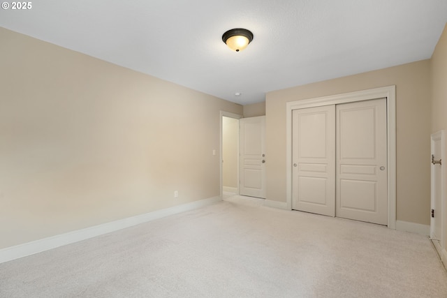 unfurnished bedroom with a closet, light carpet, and baseboards