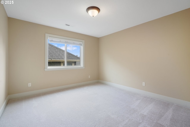 spare room featuring carpet floors, visible vents, and baseboards