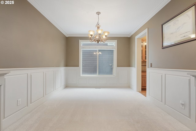 spare room featuring a chandelier, wainscoting, light colored carpet, and ornamental molding