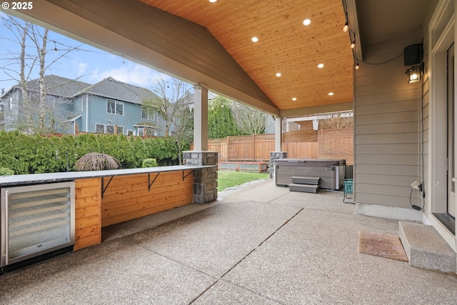 view of patio / terrace featuring a hot tub, wine cooler, and a fenced backyard