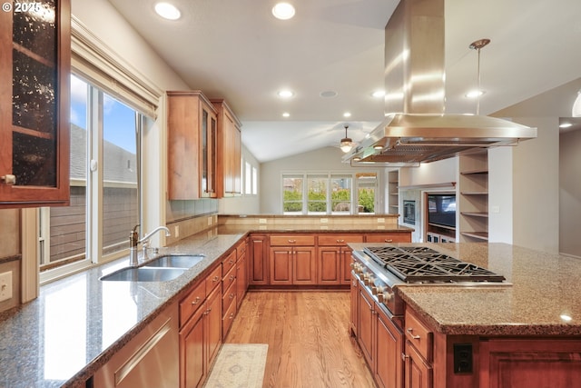 kitchen featuring island exhaust hood, glass insert cabinets, a sink, and decorative light fixtures