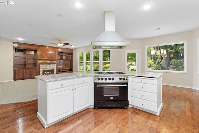 4220 NE 171st Ave, Vancouver, WA 98682 - kitchen with gas range oven, island range hood, a ceiling fan, white cabinetry, and a fireplace