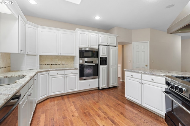 4220 NE 171st Ave, Vancouver, WA 98682 - kitchen with built in appliances, wall chimney exhaust hood, backsplash, white cabinets, and recessed lighting