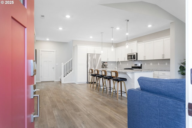 31380 NW Turel Dr, North Plains, OR 97133 - kitchen with stainless steel appliances, open floor plan, light wood-style floors, white cabinets, and recessed lighting