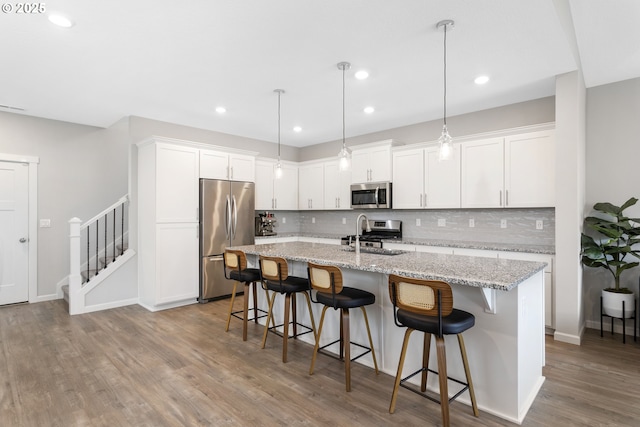 31380 NW Turel Dr, North Plains, OR 97133 - kitchen with stainless steel appliances, backsplash, a center island with sink, wood finished floors, and recessed lighting
