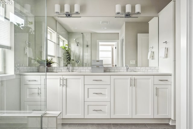 bathroom with vanity, a shower with shower door, and a healthy amount of sunlight