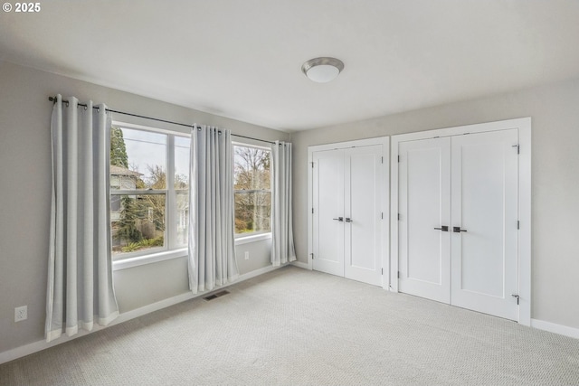 unfurnished bedroom with multiple closets and light colored carpet