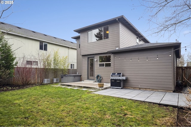 back of property with a hot tub, a patio, and a yard