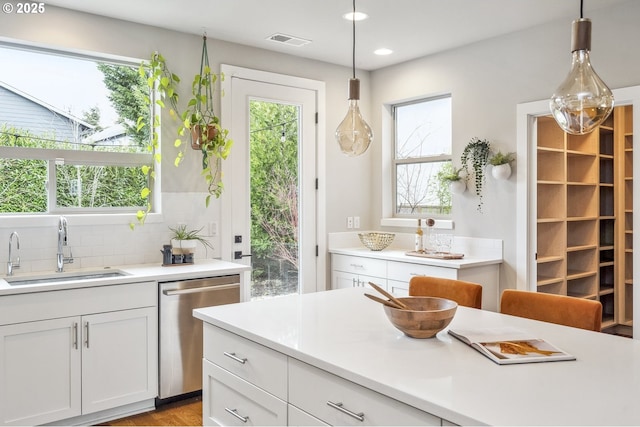 kitchen featuring white cabinetry, sink, hanging light fixtures, and dishwasher