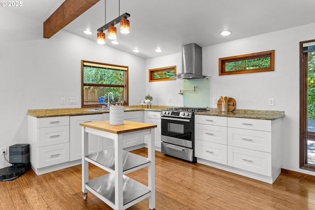 3115 NW Cornell Rd, Portland, OR 97210 - kitchen with stainless steel gas stove, wall chimney exhaust hood, a sink, light wood-style flooring, and white cabinets