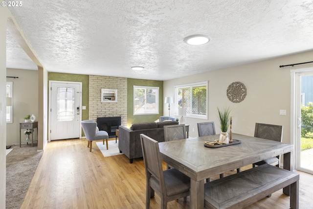 11547 NE San Rafael St, Portland, OR 97220 - dining area with light wood-style flooring, a textured ceiling, and a fireplace