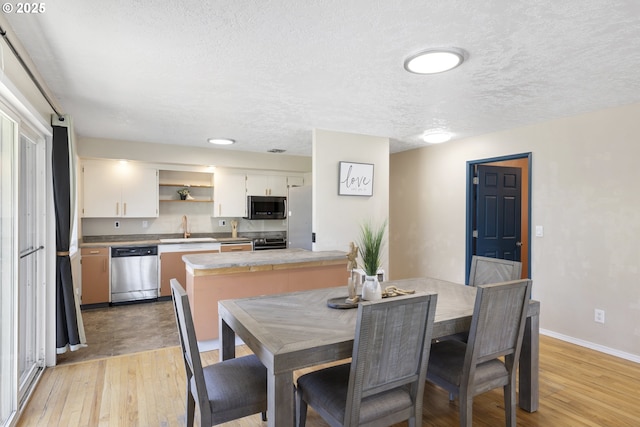 11547 NE San Rafael St, Portland, OR 97220 - dining area featuring light wood-style flooring, a textured ceiling, and baseboards