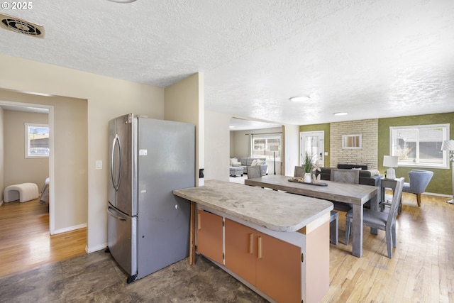 11547 NE San Rafael St, Portland, OR 97220 - kitchen with freestanding refrigerator, a textured ceiling, light countertops, open floor plan, and wood finished floors