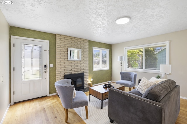 11547 NE San Rafael St, Portland, OR 97220 - living area featuring a brick fireplace, wood finished floors, a textured ceiling, and baseboards