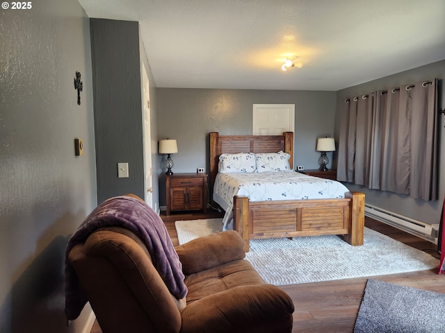 bedroom with baseboards, a baseboard heating unit, and wood finished floors