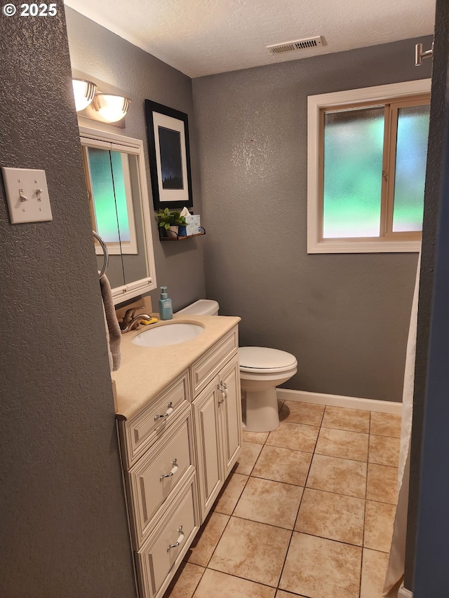 half bath featuring visible vents, tile patterned flooring, vanity, toilet, and a textured wall