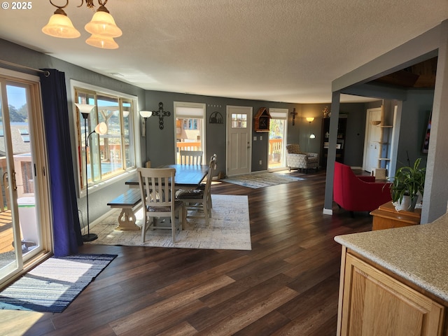 dining area featuring an inviting chandelier, a textured ceiling, and dark wood-type flooring