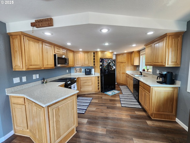 kitchen with a sink, light countertops, baseboards, black appliances, and dark wood-style floors