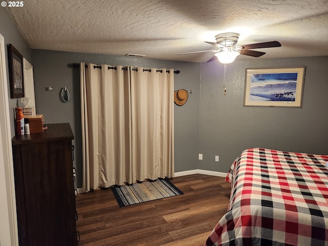 bedroom with dark wood-style flooring, a textured ceiling, a ceiling fan, and baseboards